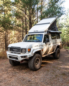 Alu-Cab Hercules white roof conversion open on a white Land Cruiser 78 Troopy in a forest